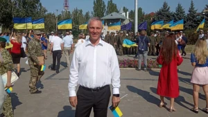 Зрадник Володимир Сальдо з українським прапором в руках на фоні українських прапорів