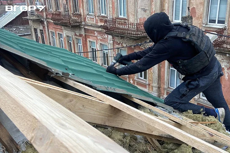 Волонтери Херсона в бронежилетах ремонтують дах в “червоній зоні” міста. Фото Олени Гнітецької / "Вгору"