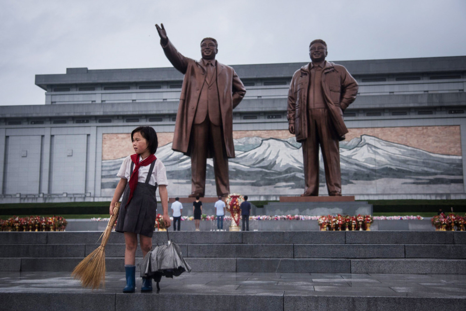 Дівчинка підмітає біля пам'ятника північнокорейських лідерів Кім Ір Сена і Кім Чен Іра в Пхеньяні 27 липня. (Photo by Ed Jones / AFP Photo)